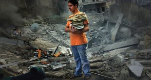 A boy saves a few books from the rubble of his home, a six storey apartment building which was bombed by the Israeli air force. The building was in the middle of a densely populated area in the city of Tyre. Three casualties were reported.