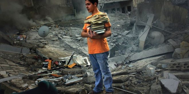 A boy saves a few books from the rubble of his home, a six storey apartment building which was bombed by the Israeli air force. The building was in the middle of a densely populated area in the city of Tyre. Three casualties were reported.