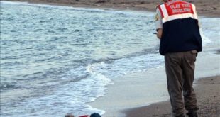 FILE - In this Wednesday  Sept  2  2015 file photo  a paramilitary police officer investigates the scene before carrying the body of 3-year-old Aylan Kurdi from the sea shore  near the beach resort of Bodrum  Turkey  A number of migrants are known to have died and some are still reported missing  after boats carrying them to the Greek island of Kos capsized   AP Photo DHA  File  TURKEY OUT